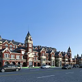 Scenic European Style Commercial Street Featuring Red Brick Buildings Towers And Cars On Road