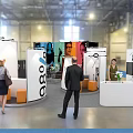 Modern Exhibition Booth Design With Modular White Orange Panels And Interactive Visitor Areas