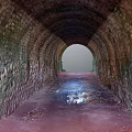 Brick Tunnel Architecture With Moss Covered Walls Red Floor Puddle And Light At End