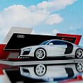 Silver Audi R8 Spyder on Display Platform with Red Black Design and Blue Sky Clouds