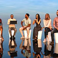 Group of People with Laptop Sitting on White Stools under Blue Sky with Reflections