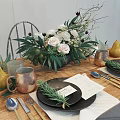 Elegant Tableware Set with Copper Mugs Black Plates Rosemary and Floral Arrangement on Wooden Table