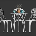White Metal Outdoor Table With Intricate Cutout Chairs Orange Vase Blue Cups And Flower Decoration