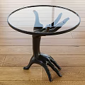 Glass Top Side Table with Black Claw Shaped Base on Wooden Floor