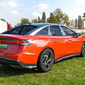 Volkswagen Electric Car Parked On Grass Near Red Barn And Trees