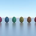 Six Colorful Sparkling Egg Shaped Decorative Ornament Set Arranged On Smooth Surface Against Blue Sky