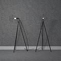 Two Black Tripod Floor Lamps Placed Against Gray Wall With Gray Floor And White Baseboard
