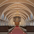 Church Interior With Arched Ceiling Stained Glass Windows Central Pipe Organ Wooden Pews Red Carpet