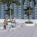People Gathered Around Circular Metal Structure With Potted Plants And Stones