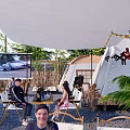 Relaxing Evening Camping Site With Palm Trees Tent Outdoor Seating String Lights And Large Screen