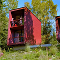 Red Cube Shaped Guesthouse Building Nestled in Forest with Balcony and Greenery