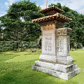 Ancient Carved Stone Pillar Standing in Lush Green Grassland With Surrounding Trees