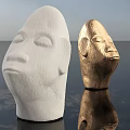 White And Golden Head Sculptures With Carved Facial Features And Water Reflections