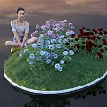 Woman Squatting By Purple Blue Red Flowers On Round Green Lawn With Sunset Sky Reflection