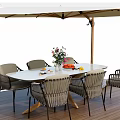 Outdoor Table with Woven Chairs Flower Vase Fruits and Umbrella on Wooden Deck