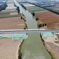 High Speed Railway Bridge Over River With Farmland And Passing Train