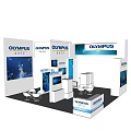 OLYMPUS Exhibition Booth With Modern White Design Display Screens Tables Chairs And Brand Logos
