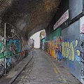 Vibrant Commercial Street Featuring Graffiti Covered Buildings Cobblestone Path and Distant Archway