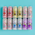 Assorted Flavored Canned Beverages With Vibrant Packaging On Light Blue Background