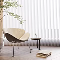 Upholstered Accent Chair with Potted Plant White Blinds Wooden Floor Small Round Table and Books