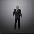 Bald Man in Black Suit and Tie Standing Against Gray Background