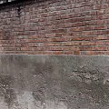 Building Exterior Wall With Red Bricks Upper Section Gray Concrete Middle Layer And Weathered Texture