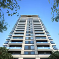 High Rise Modern Residential Building With Glass Balconies Greenery And Blue Sky
