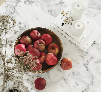 Fresh Red Apples in Wooden Bowl Alongside Books Candles and Dried Flowers on Marble Countertop 3d model