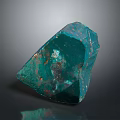 Green Raw Stone with Copper Spots and Natural Texture on Dark Reflective Surface