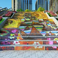 Colorful Outdoor Stairs With Artistic Graffiti Surrounded By Flowers And Tall Buildings