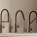 Three Modern Brushed Brass Faucets With Black Curved Spouts On Light Countertop