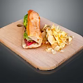 Fresh Baguette Sandwich With Lettuce And Tomato Served With Potato Chips On Wooden Cutting Board