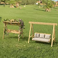 Outdoor Wooden Swing Chairs With Vine Flower Decor And Striped Cushions On Green Grass
