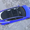 Blue Modern Sedan with Sleek Design and Black Wheels on Urban Cobblestone Street