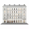 Multi Story White Residential Building Featuring Ornate Details Ground Floor Storefronts And Lit Windows