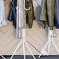 Stylish Clothes Hangers With Hanging Clothes Bags And Hats Against Geometric Patterned Wall
