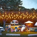 Comfortable Garden Landscape Camping Site With Warm String Lights And Happy Family Outdoor Gathering