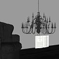 Black Chandelier With Candle Style Lights Above Open Book And Leather Sofa
