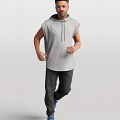 A Man Wearing Gray Sleeveless Hoodie And Dark Pants Standing Casually Against Simple Background