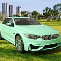 Light Green BMW M4 Coupe on Grassy Lawn with Tall Buildings Background
