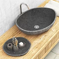 Black Stone Sink with Silver Faucet on Wooden Countertop and Stone Containers Against Gray Wall