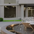 Multi Tiered Water Fountain In Front Of Modern Building With Glass Windows And Green Shrubs