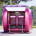 Outdoor Pink Can Shaped Kiosk With Display Shelves And Green Surroundings