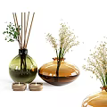 Glass Vases In Green And Amber Holding Small White Flowers Green Foliage And Small Candles
