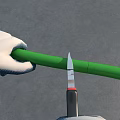 Man Wearing White Gloves Carefully Cutting Green Pipe With Utility Knife