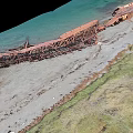 Aerial View Coastal Scenery Featuring Shipwreck Remains Sandy Beach Green Grass And Clear Blue Water