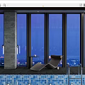 Modern Poolside Lounge Chair With Small Table By Large Windows At Night