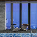 Modern Poolside Lounge Chair With Small Table By Large Windows At Night