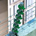 Industrial Security Barbed Wire Fence With Green Insulators Yellow Warning Signs And Concrete Base