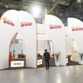 Jamies Exhibition Booth Featuring White Curved Structure Orange Branding Plants And Staff